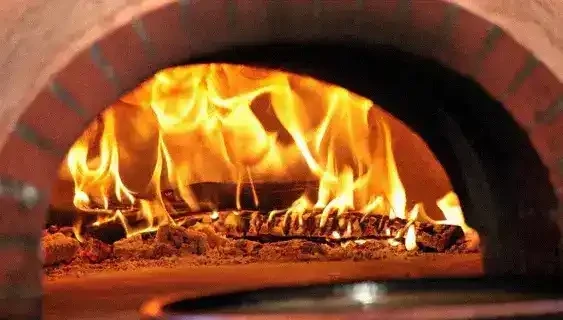 Foto de un horno de leña encendido y una comida familiar