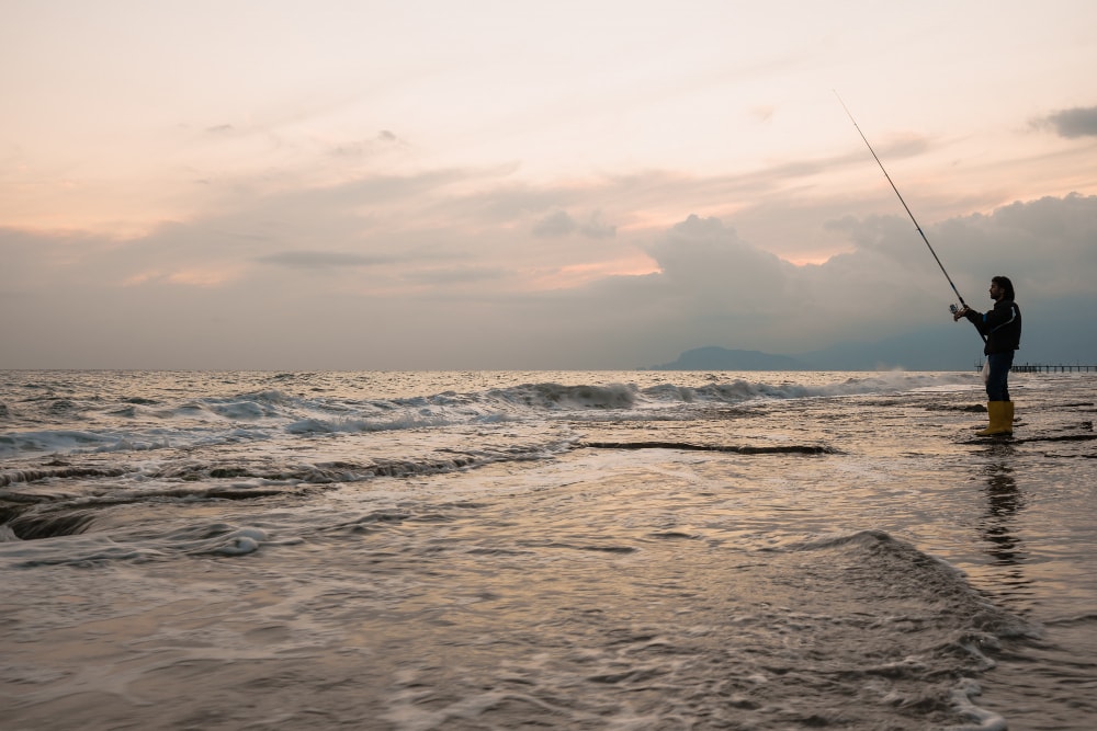 Foto de un pescadr en el amanecer en una playa
